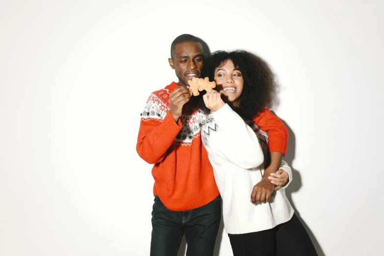 a man and a woman posing for a picture, by Carey Morris, pexels, sweater, gingerbread people, long orange sweatshirt, black people