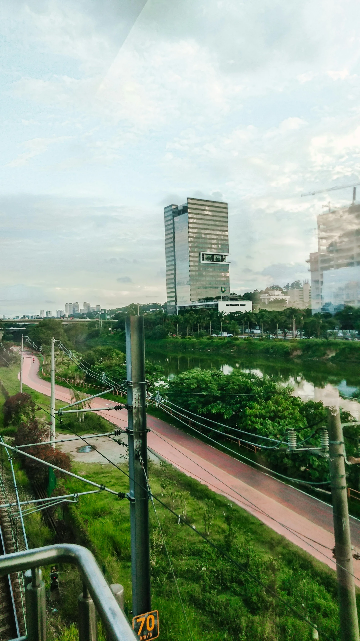 a train traveling down train tracks next to tall buildings, by Basuki Abdullah, panorama view, low quality photo, cinematic shot ar 9:16 -n 6 -g, scenic view of river