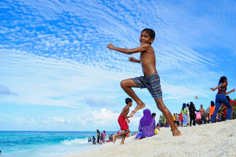 a young boy standing on top of a sandy beach, pexels contest winner, hurufiyya, local people chasing to attack, maldives in background, mana in the air, childish gambino