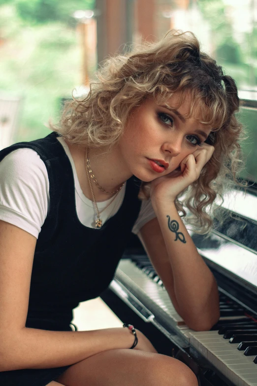 a woman sitting in front of a piano, an album cover, inspired by Rhea Carmi, trending on pexels, photorealism, 8 0 s haircut, sydney sweeney, curls, tattooed