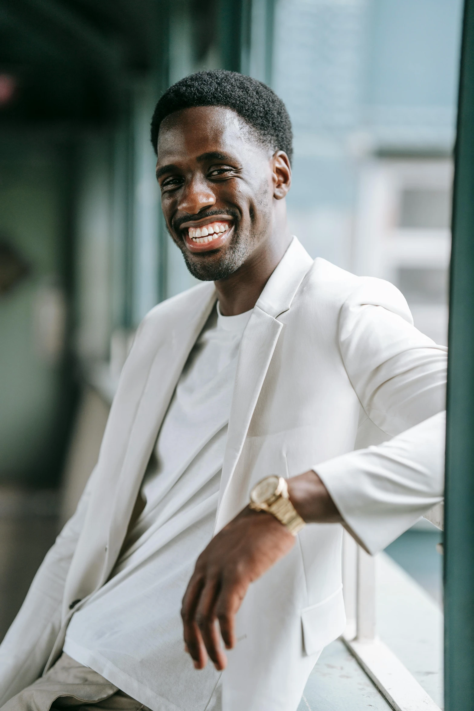 a man in a white suit sitting on a window sill, by Stokely Webster, smiling confidently, jaylen brown, portrait featured on unsplash, aaron rodgers