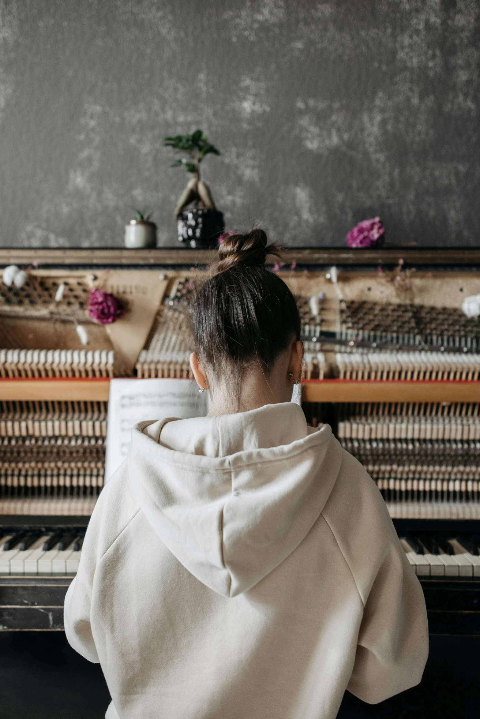 a person sitting in front of a piano, facing away from the camera