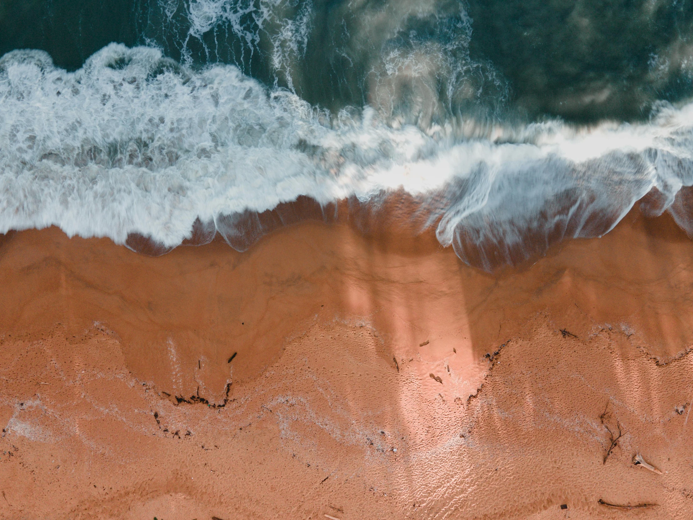 a person riding a surfboard on top of a sandy beach, pexels contest winner, minimalism, red sand beach, volumetric light from above, photo of the middle of the ocean, erosion