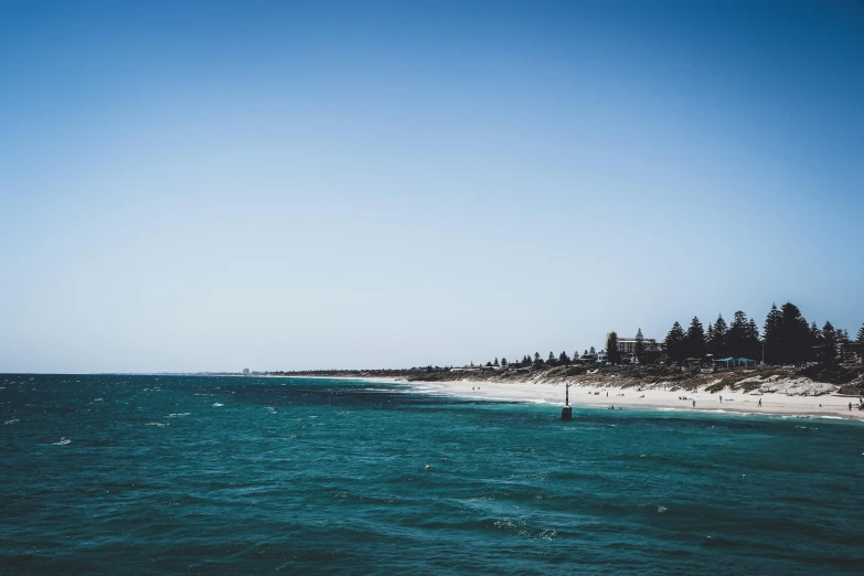 a body of water next to a sandy beach, by Peter Churcher, unsplash, clear blue sky vintage style, port city, kimberly asstyn, viewed from very far away