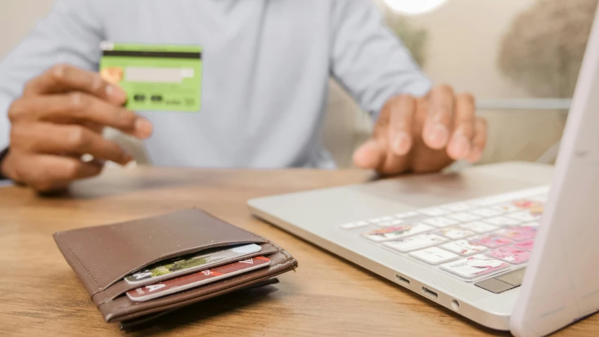a man holding a credit card in front of a laptop, by Carey Morris, pexels, figuration libre, a green, brown, coloured photo, instagram post