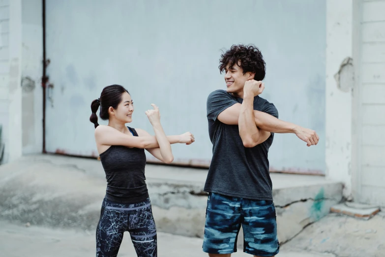 a man and a woman standing next to each other, pexels contest winner, happening, dynamic stretching, half asian, woman holding another woman, arms to side