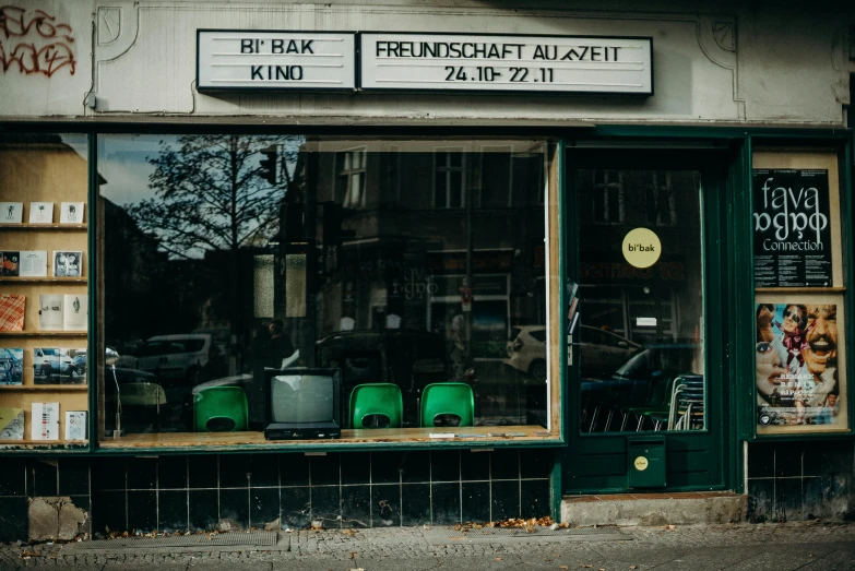 a green car parked in front of a book store, unsplash, arbeitsrat für kunst, restaurant, 1990's photo, food stall, old building