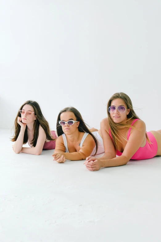 a group of women laying on top of a white floor, an album cover, in sun glasses, kailee mandel, in a photo studio, thicc