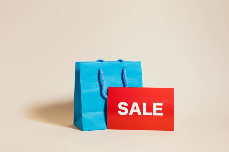 a blue shopping bag sitting next to a red sale sign, trending on unsplash, material design, thumbnail, digital image, luxury brand
