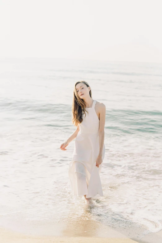 a woman standing on top of a beach next to the ocean, ivory pale skin, wearing a dress made of water, looking happy, wavy