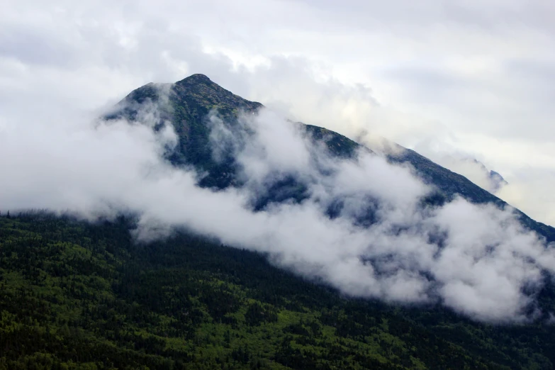 a mountain covered in clouds on a cloudy day, unsplash, hurufiyya, alaska, 2000s photo, multiple stories, smoke - filled ， green hill