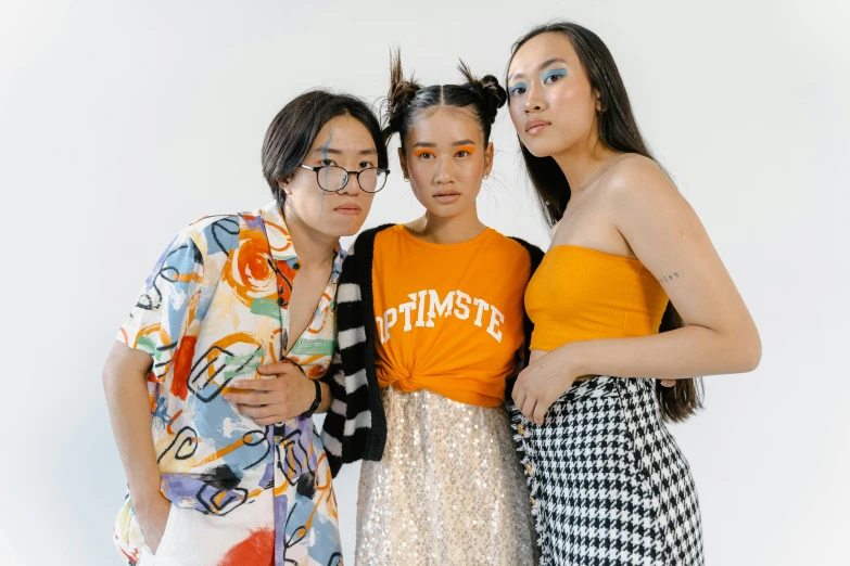 a group of three women standing next to each other, inspired by Mattise, trending on pexels, kitsch movement, half asian, resembling a mix of grimes, in front of white back drop, colourful clothes