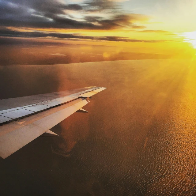 an airplane wing flying over a body of water, pexels contest winner, golden glow, instagram picture, blocking the sun, runway