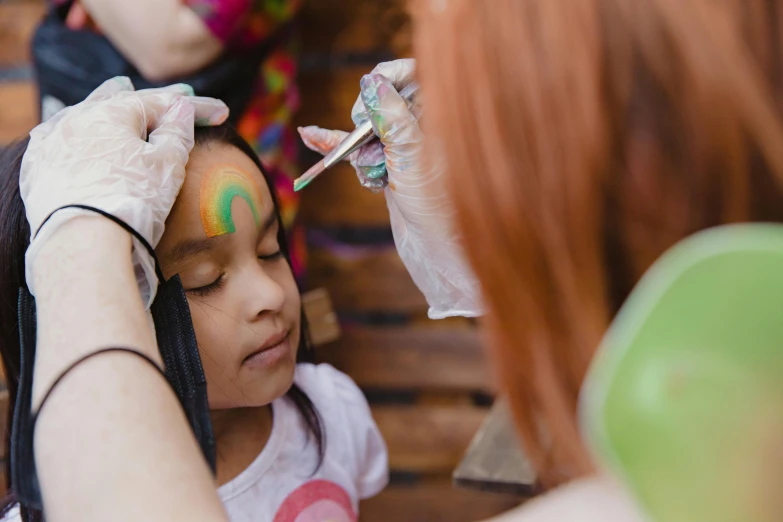a little girl getting her face painted by a woman, pexels contest winner, thumbnail, head down, avatar image, cute girls