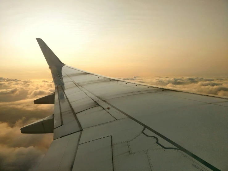 the wing of an airplane flying above the clouds, by Jessie Algie, pexels contest winner, happening, on the runway, fused aircraft parts, hd footage, looking off into the sunset