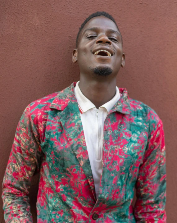 a man standing in front of a brown wall, by Jessie Alexandra Dick, trending on unsplash, happening, wearing a colorful men's suit, smiling maniacally, adut akech, historical photo