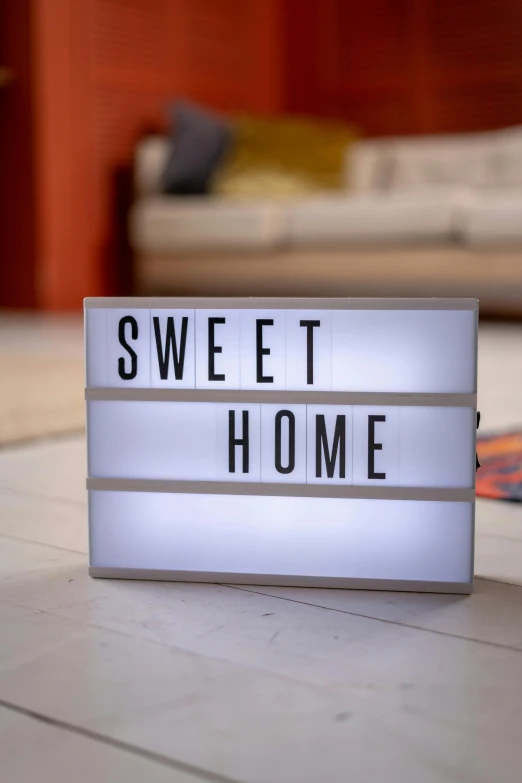 a white light box sitting on top of a wooden floor, by Helen Stevenson, shutterstock, sweet home, sign, fully decorated, close up shot from the side