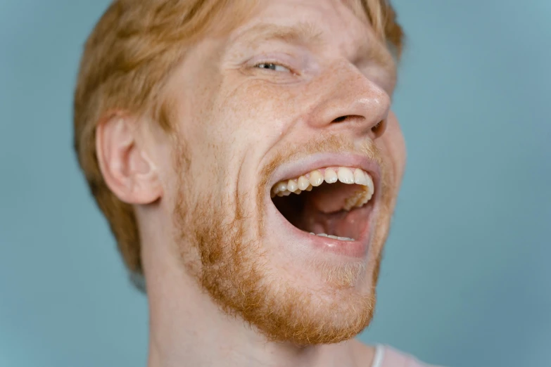 a close up of a person with a tooth brush in their mouth, an album cover, trending on pexels, hyperrealism, hr ginger, laughing man, light freckles, mouth is simple and pleasant