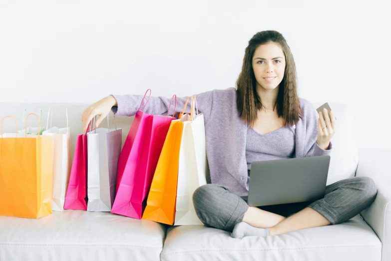 a woman sitting on a couch with shopping bags and a laptop, pexels, 🦩🪐🐞👩🏻🦳, sitting in an empty white room, multi - coloured, customers