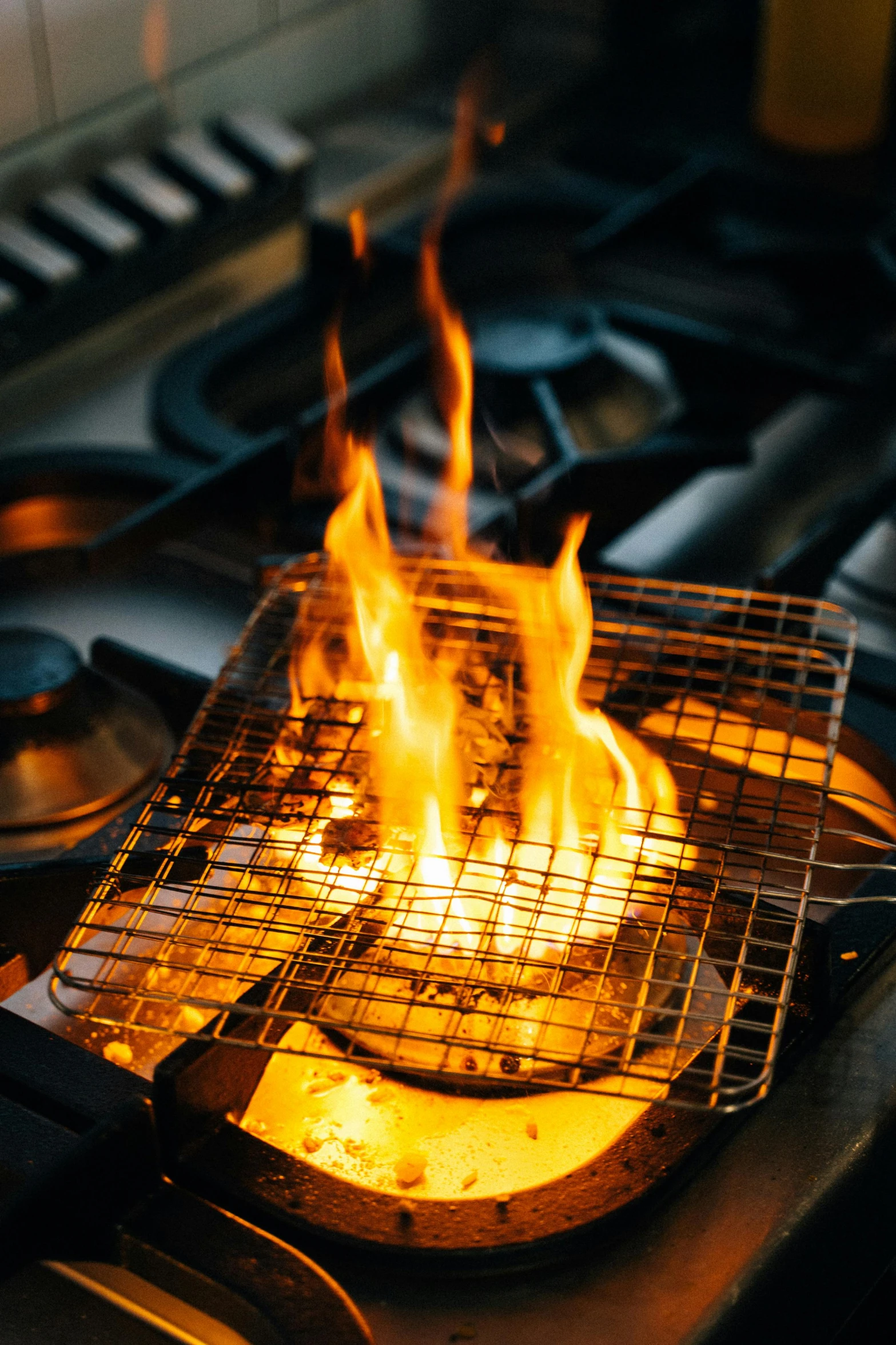 a close up of a frying pan on a stove, with fire, floor grills, lynn skordal, doff