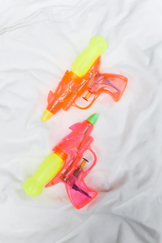 a couple of water guns laying on top of a bed, multi - coloured, mint