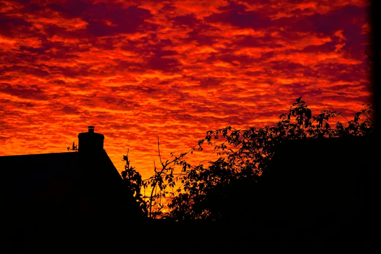 a silhouette of a house with a red sky in the background, by Kev Walker, pexels contest winner, orange clouds, shot from roofline, vibrant orange, fine art print