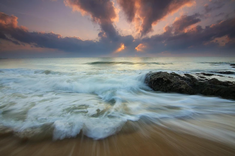 a large body of water sitting on top of a sandy beach, by Reuben Tam, unsplash contest winner, waves crashing at rocks, epic sunrise, turbulence, 8k fine art photography