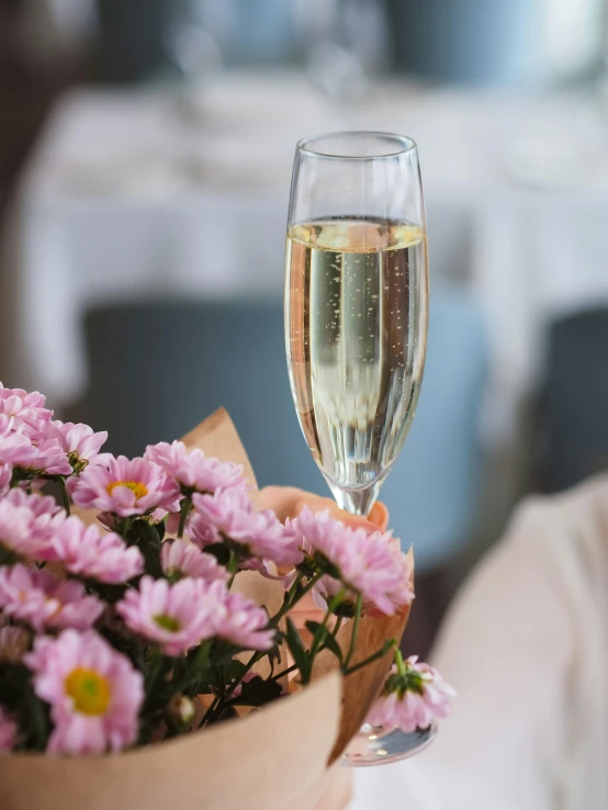 a glass of wine sitting on top of a table, holding flowers, bubbly, all overly excited, zoomed in