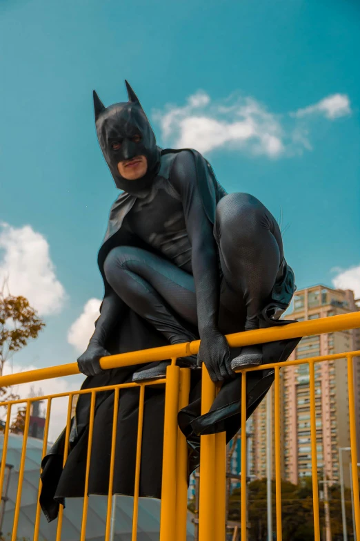 a batman statue sitting on top of a yellow fence, a statue, wearing a black catsuit, in hong kong, lycra costume, full body 8k