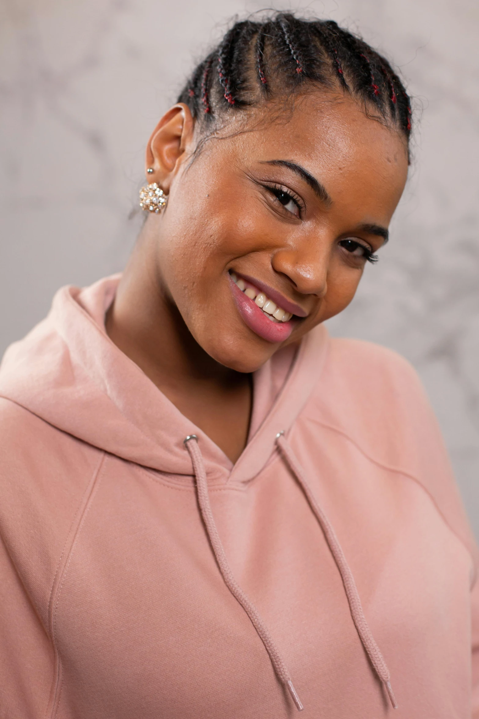 a woman in a pink hoodie smiles at the camera, inspired by Sophia Beale, trending on pexels, studio photoshoot, ( ( brown skin ) ), avatar image, shaven