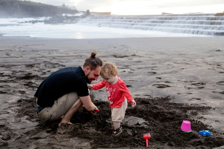 a man and a little girl playing in the sand, by Adriaen Hanneman, pexels contest winner, iceland, profile image, eva elfie, playing with the water