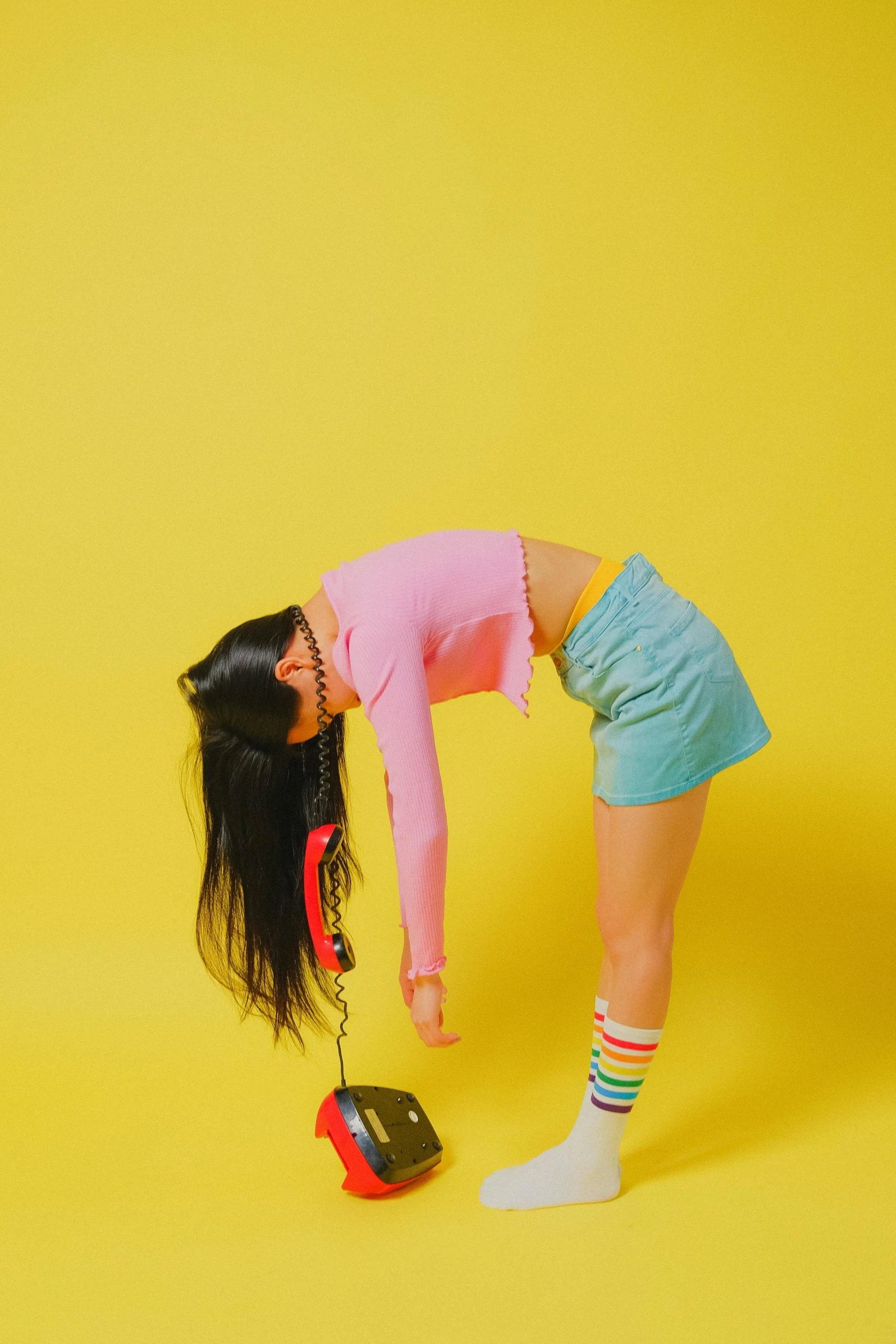 a woman bending over to pick up a pair of shoes, an album cover, inspired by Ren Hang, trending on pexels, magic realism, colorful pigtail, pink and yellow, girl with black hair, toys