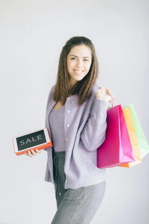 a woman holding shopping bags and a sale sign, a colorized photo, pexels contest winner, she is holding a smartphone, on a gray background, wearing business casual dress, pastel clothing