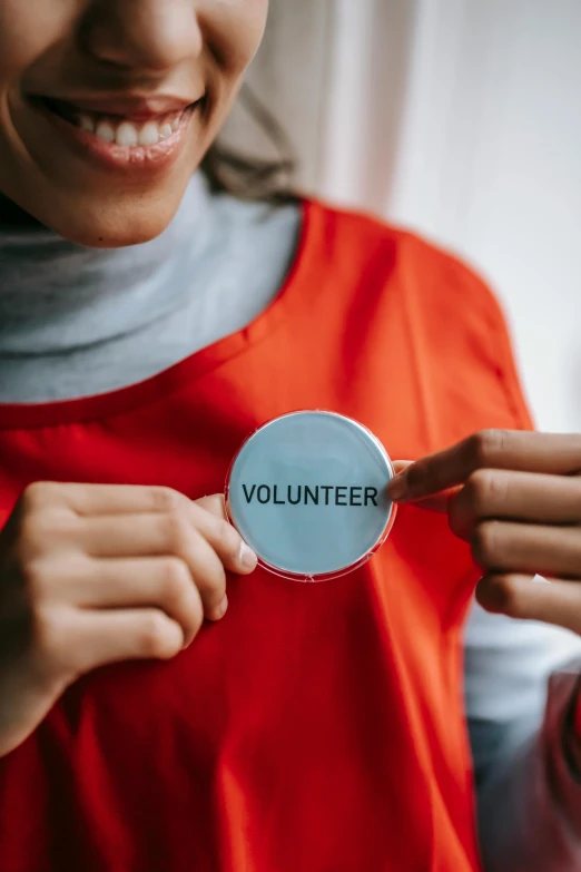 a woman holding a badge that says volunteer, pexels contest winner, happening, round-cropped, paul barson, label, holding wand