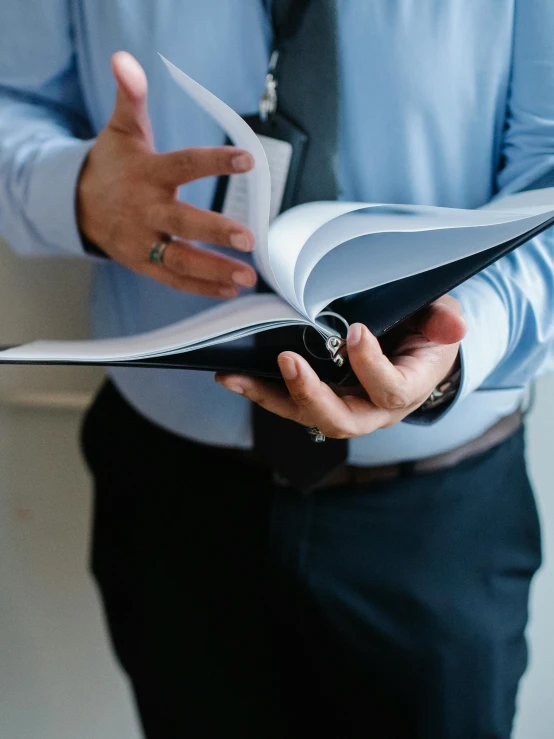 a man in a blue shirt and tie holding a book, by Carey Morris, trending on unsplash, maintenance photo, thumbnail, holding a giant book, multiple stories