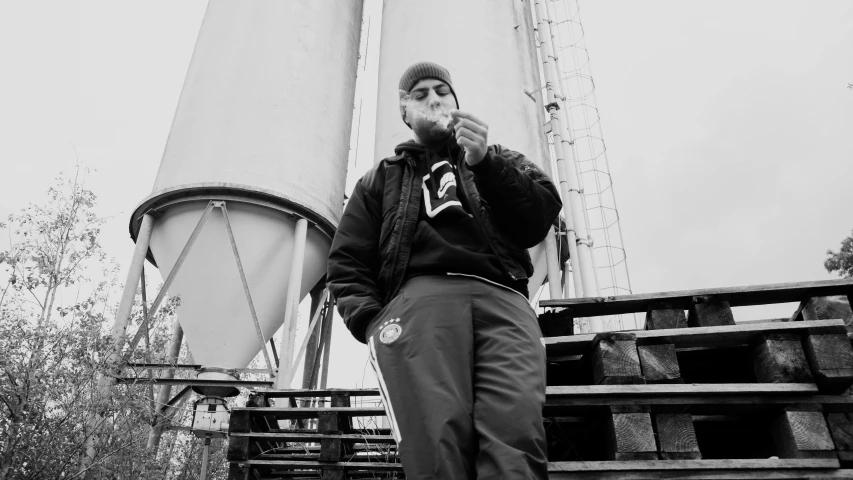 a black and white photo of a man smoking a cigarette, a black and white photo, inspired by Josef Šíma, unsplash, graffiti, chappie in an adidas track suit, standing on ship deck, mac miller, promotional image