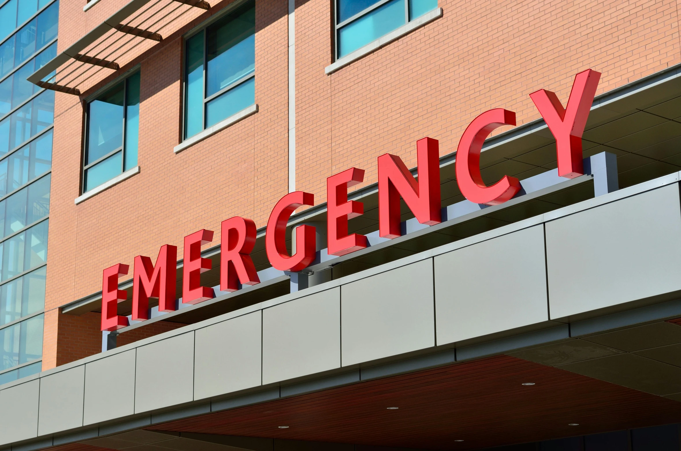 a red emergency sign on the side of a building, by Meredith Dillman, pexels, surgery table, wide high angle view, profile image, multiple stories