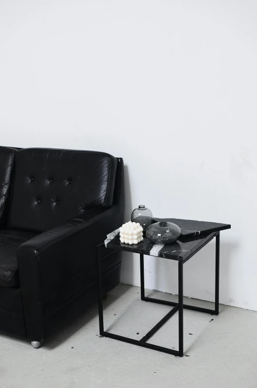 a black couch sitting in a living room next to a table, inspired by Constantin Hansen, unsplash, minimalism, made of liquid metal and marble, angle view, square, ilustration