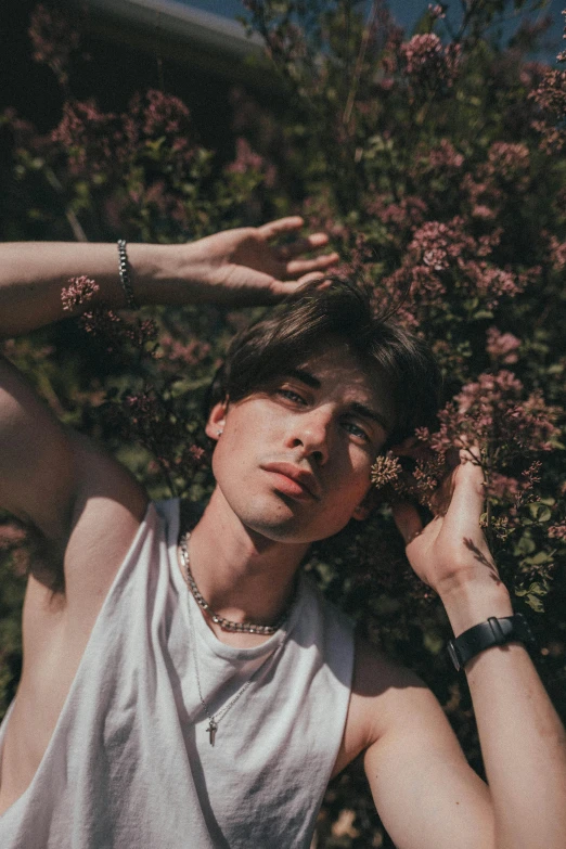 a man standing in front of a bush with his hands on his head, an album cover, by Cosmo Alexander, pexels contest winner, aestheticism, declan mckenna, portrait of a beautiful person, laying on roses, portrait androgynous girl