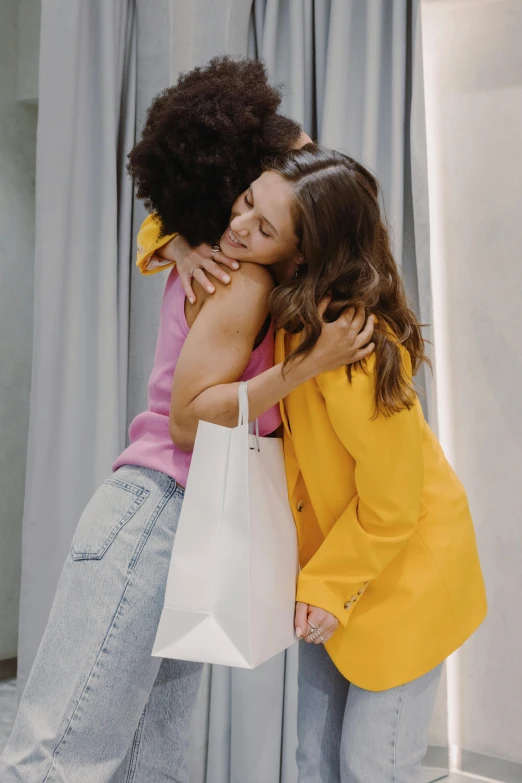 a couple of women standing next to each other, hugging and cradling, best of retail, no text, bag