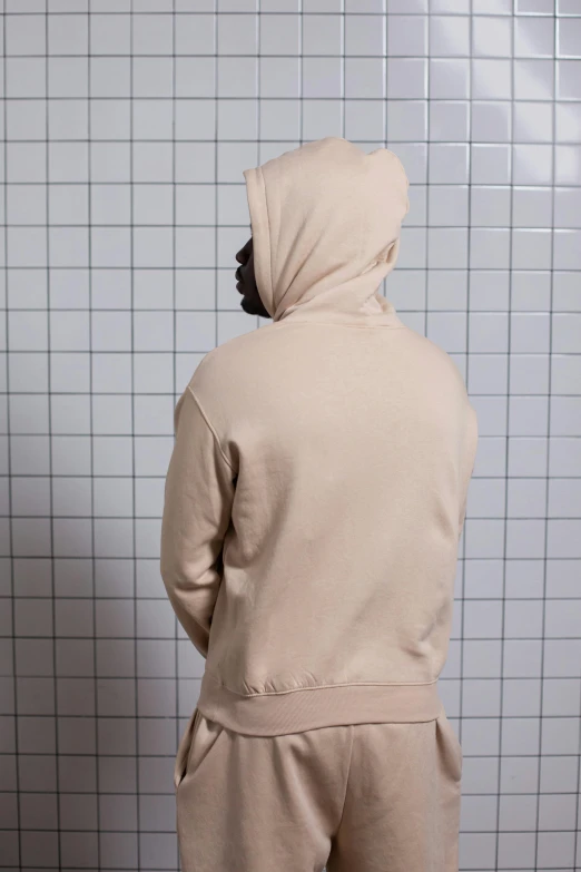 a man standing in front of a toilet in a bathroom, by Nina Hamnett, beige hoodie, back view. nuri iyem, high-body detail, zoomed out to show entire image