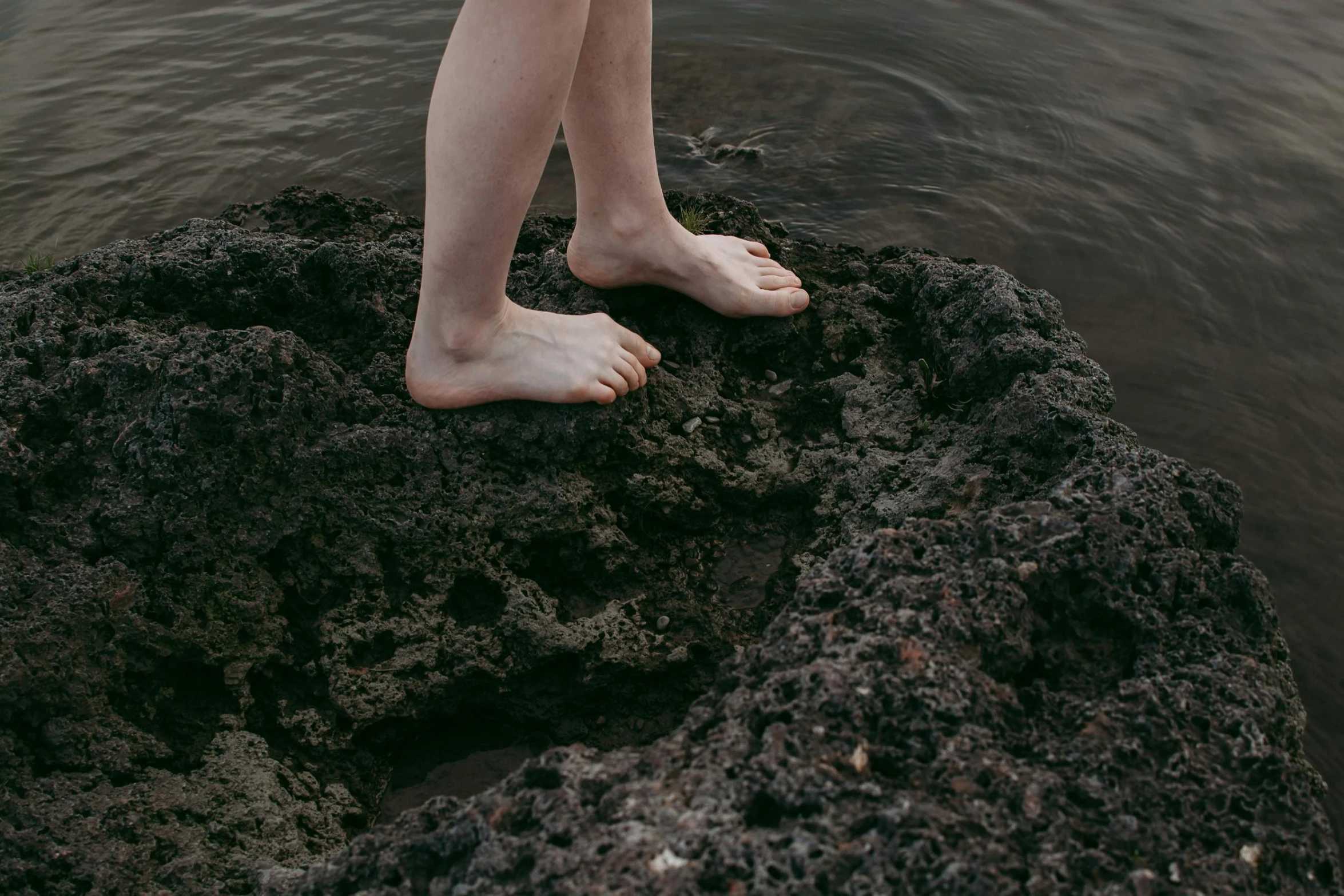 a person standing on a rock in the water, by Elsa Bleda, naturalism, real human feet, brown, low detail, modeled