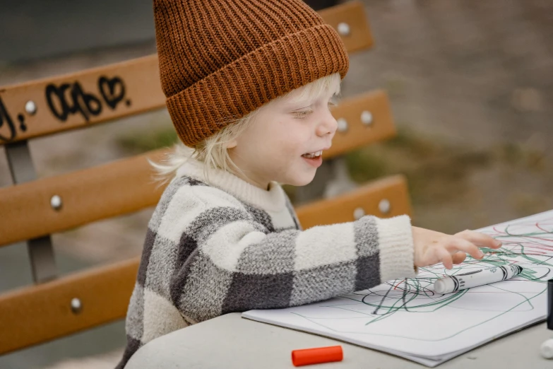 a little boy that is sitting at a table, a child's drawing, by Jesper Knudsen, pexels contest winner, knitted hat, at the park, he is wearing a brown sweater, on a canva