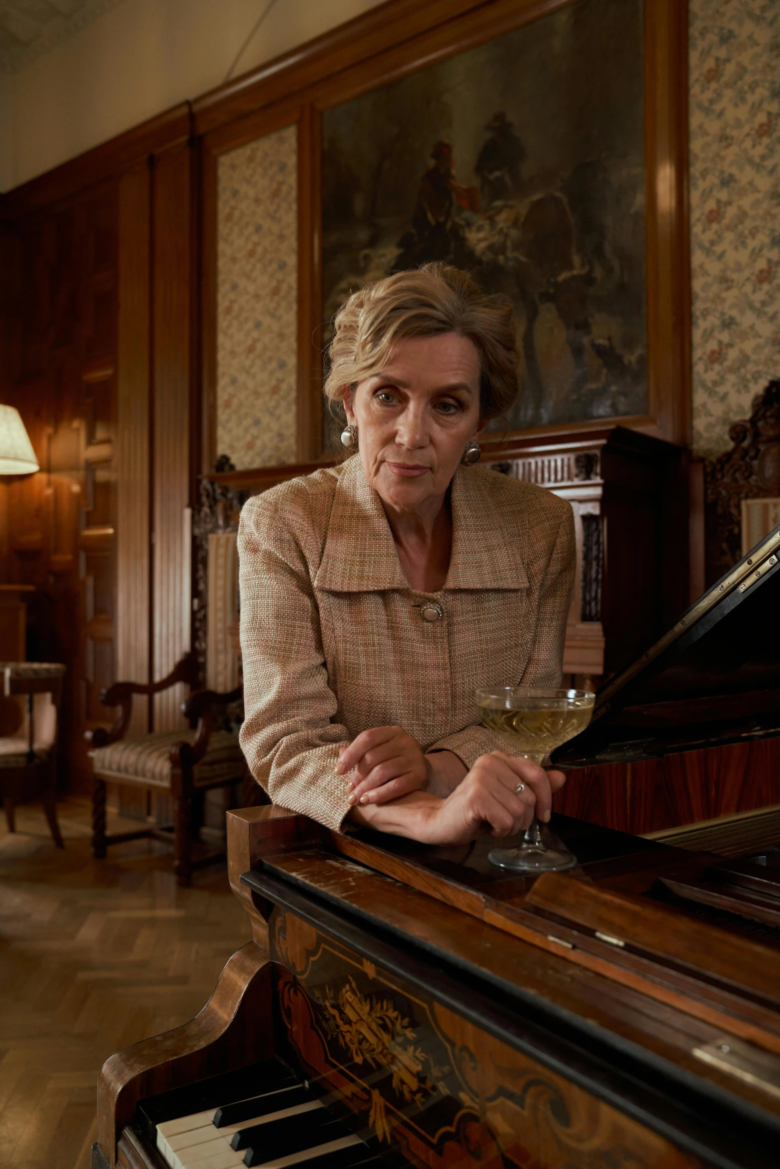 a woman sitting at a piano in a living room, the crown, she holds a glass of wine, archer, extreme drama