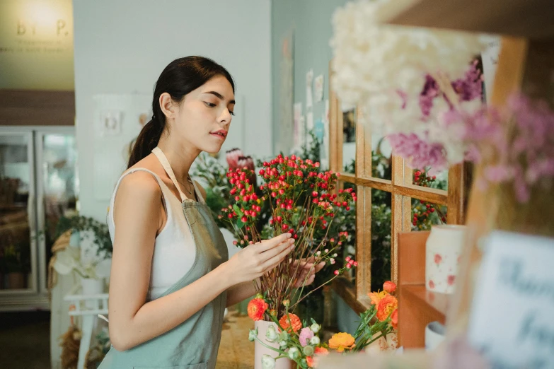 a woman standing in front of a window holding a bunch of flowers, pexels contest winner, inspect in inventory image, at the counter, avatar image, asian female