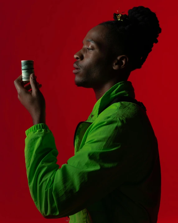 a man in a green jacket holding a can of soda, unsplash, visual art, dark skinned, offering the viewer a pill, non binary model, red and green palette
