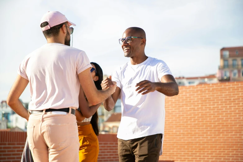 a couple of men standing next to each other, pexels contest winner, happening, rooftop party, varying ethnicities, background image, smiling at each other