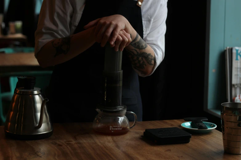 a man that is standing in front of a table, inspired by Richmond Barthé, unsplash, pouring, pot, aussie baristas, completely dark