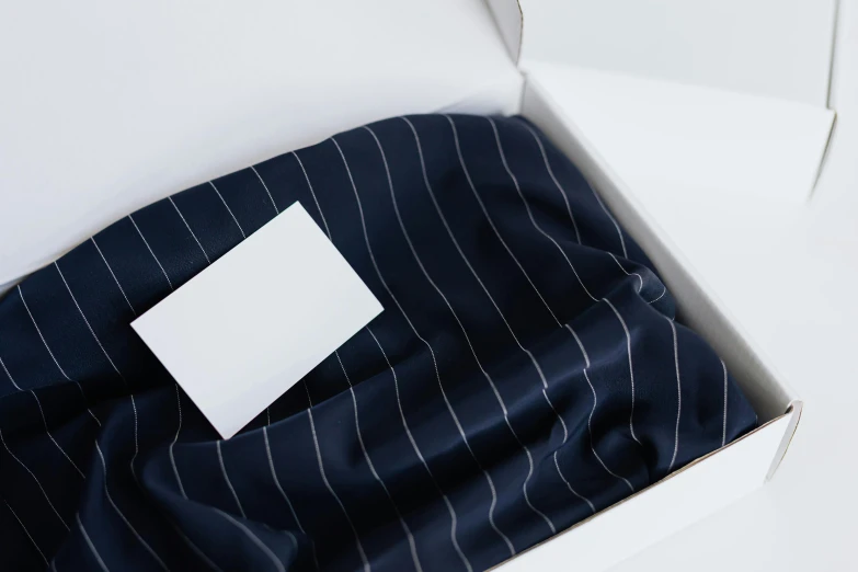 a box that has a piece of paper in it, by Eden Box, wearing a pinstripe suit, long flowing fabric, navy, product shot