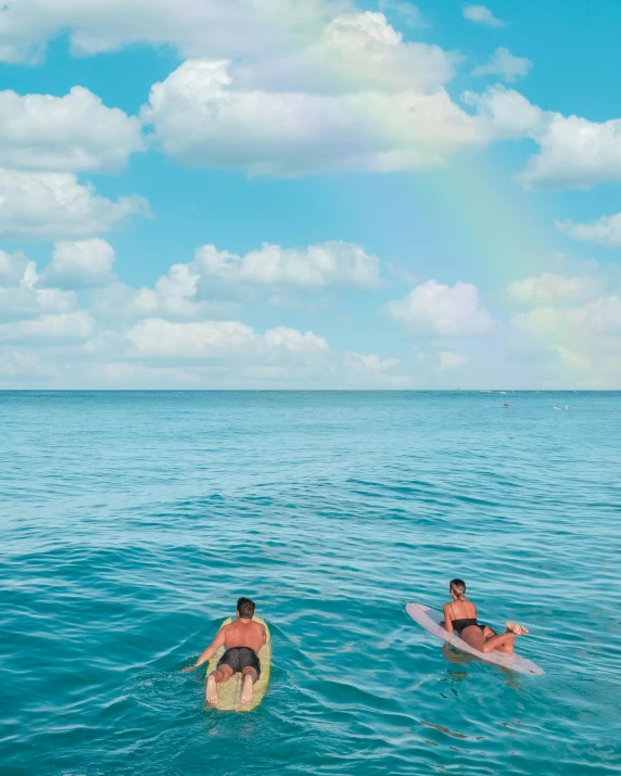 a couple of people riding surfboards on top of a body of water, sitting on top of a rainbow, miami beach, in the ocean